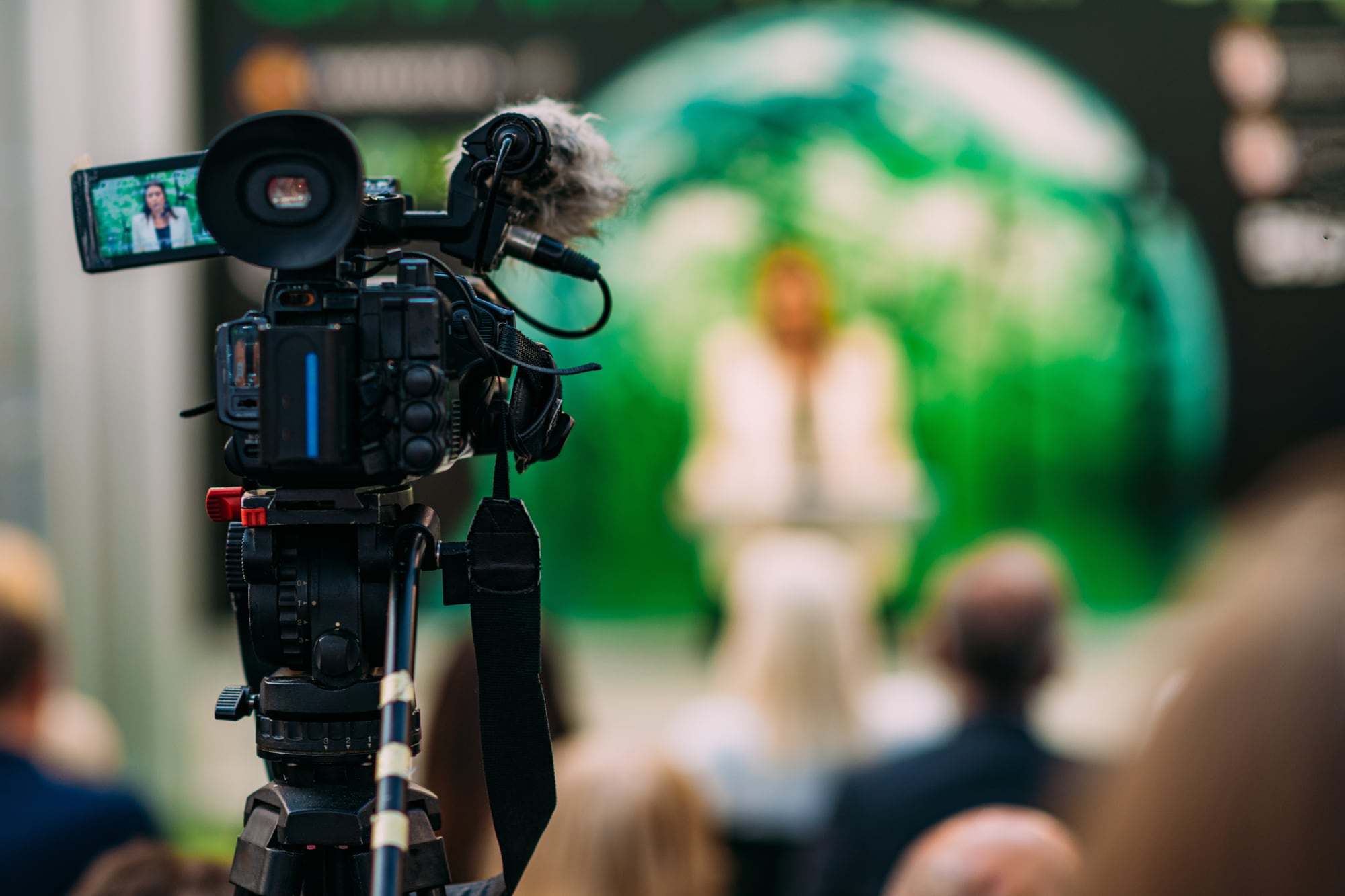 Een videocamera filmt een spreker op een congres