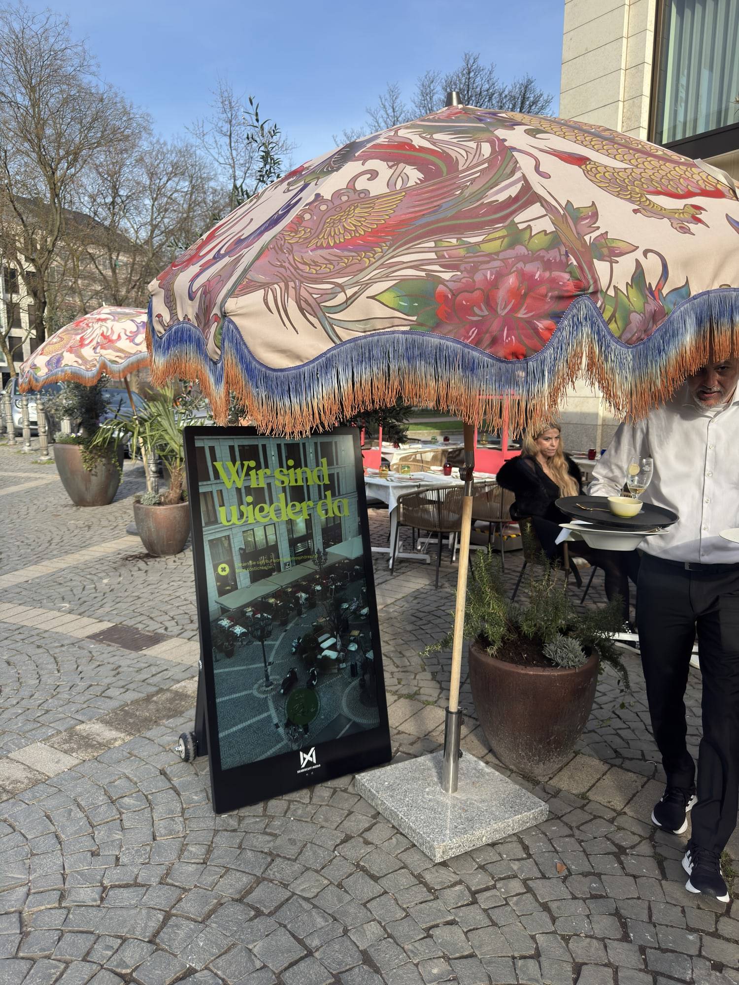 Seabiscuit-scherm naast een kleurrijke parasol op een plein met kinderkopjes