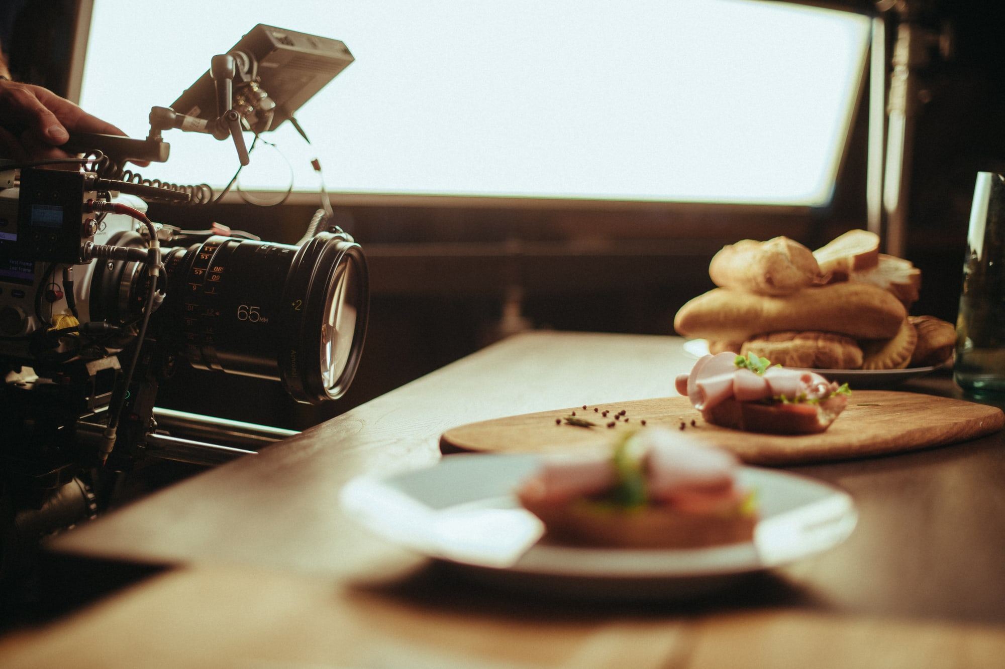 A cinema camera filming sandwiches on a wooden board for new display content