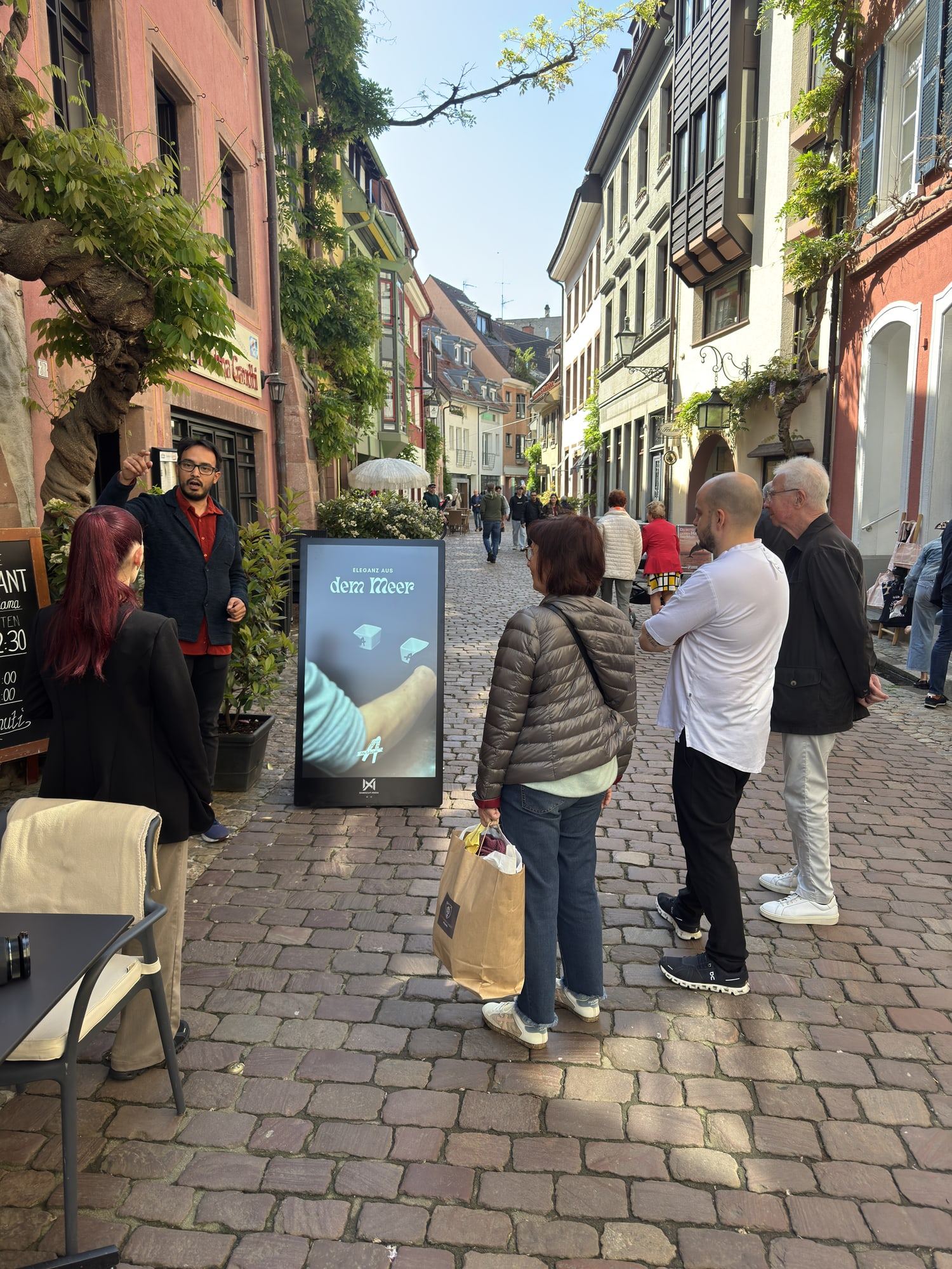 People walking past a Seabiscuit display on a busy cobbled shopping street