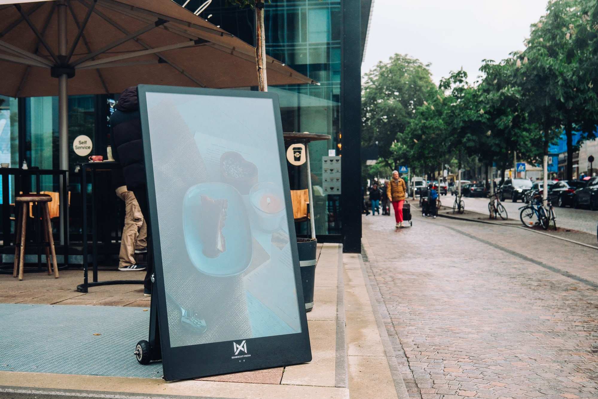 A Seabiscuit display on the pavement outside a café terrace on a city street
